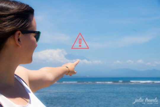 Julia zeigt von der Ferne auf den Vulkan Mount Agung in Bali
