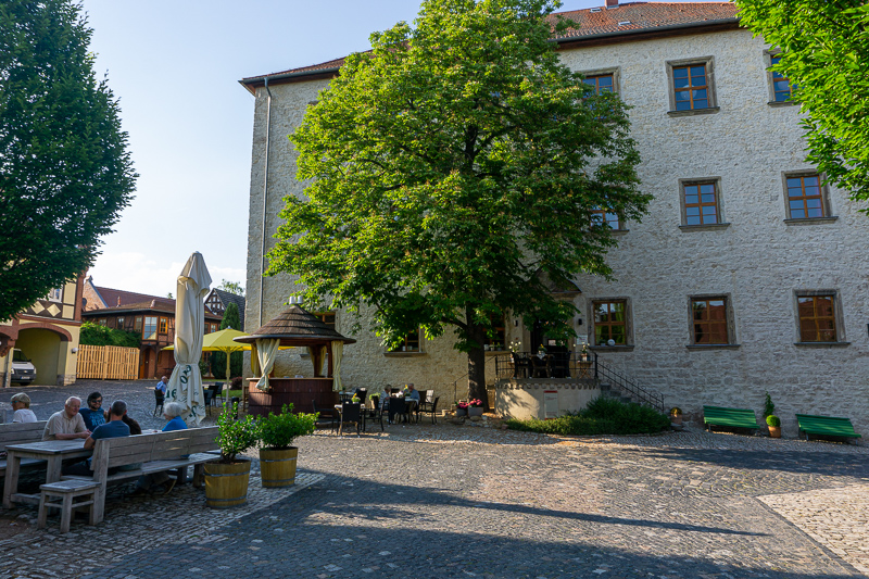 Abendstimmung auf dem Innenhof des Restaurant "Reinhardt's im Schloss". Die Restaurantgäste sitzen gemütlich auf den Bänken.