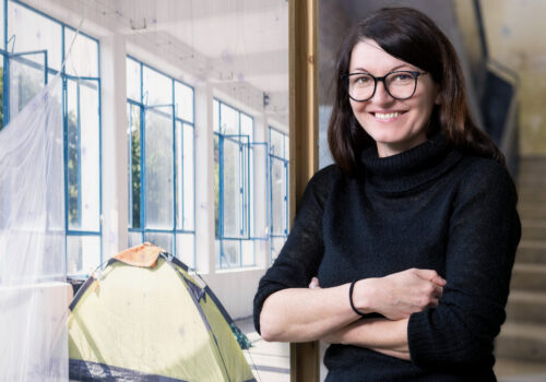 Portrait von Julia Eschment, die an einem Bild im Eiermannbau Apolda lehnt.