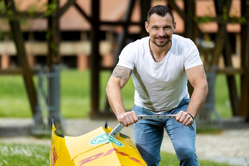 Martin Putze steht an einem gelben Bob an der ausgeklappten Schiebe-Stange.